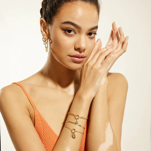 A model posed with her arms displaying several bracelets with charms connected