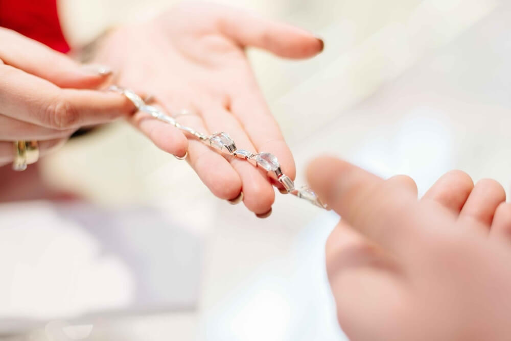 A jeweler inspects a silver bracelet a client has brought in for consignment.