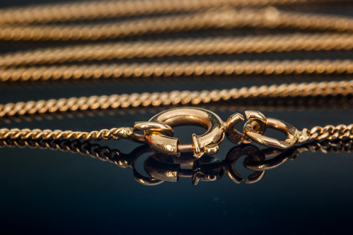 A close-up shot of a yellow gold clasp on a chain necklace