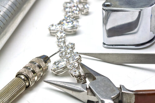 A close-up of a diamond bracelet and jeweler's tools used for bracelet repair