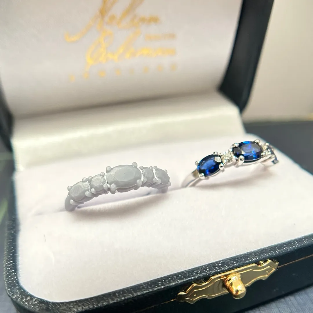 A custom design wax model of a sapphire and diamond band displayed next to the finished piece