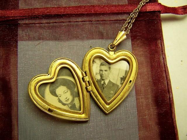 An antique gold heart locket with an image of a woman on the left and a man on the right.