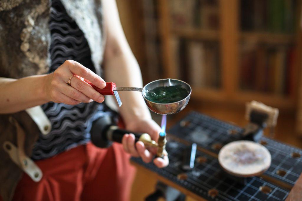 An artisan heats an enamel paste in her workshop.