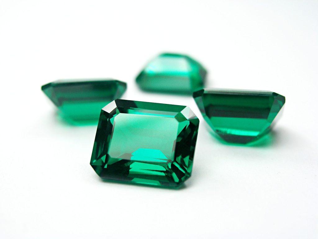 Loose emerald-shaped emerald gemstones on a white background