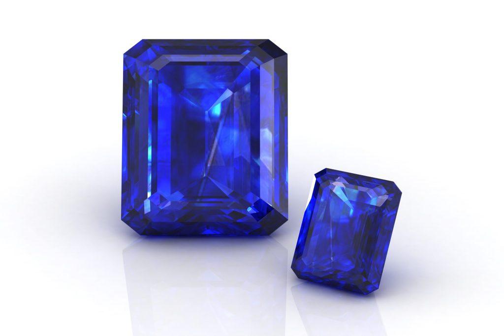 Two loose emerald-shaped blue sapphire on a white background
