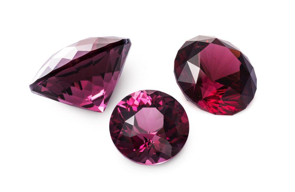 Three faceted red rhodolite garnets isolated on white background
