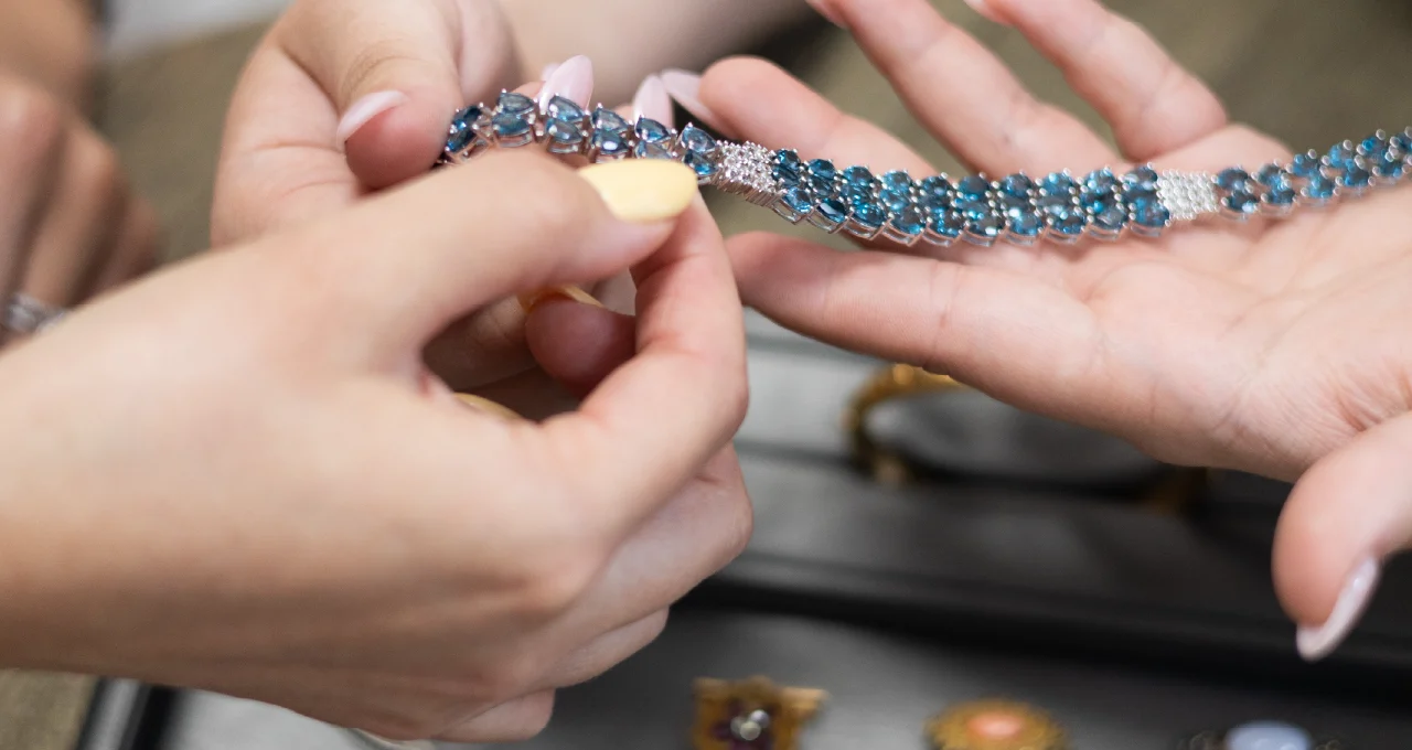 examining a bracelet among gold, silver, and platinum jewelry sorted on a tray for sale or trade-in