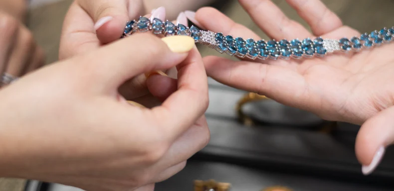 examining a bracelet among gold, silver, and platinum jewelry sorted on a tray for sale or trade-in