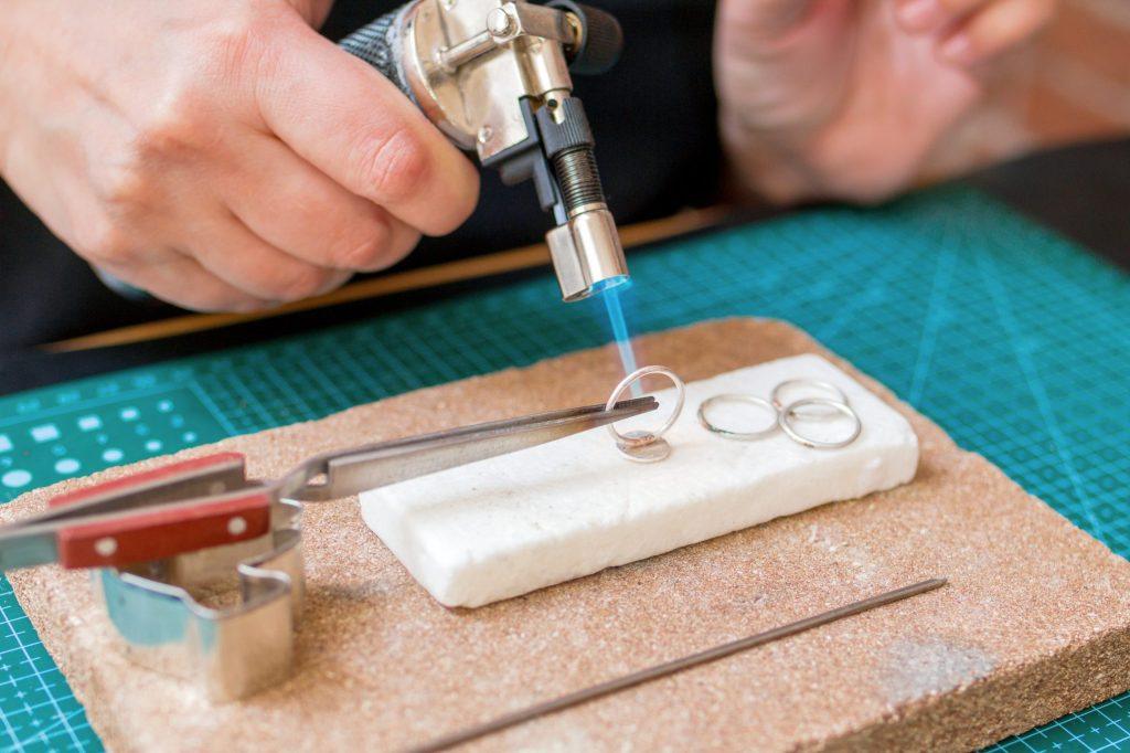 A close-up shot of a woman completing a jewelry repair using soldering.
