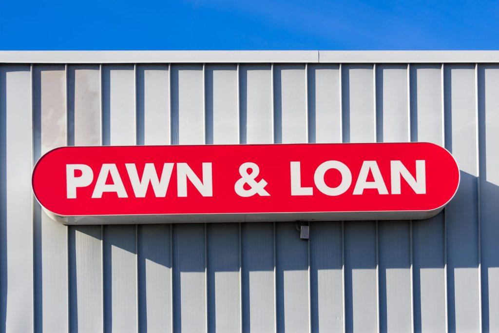 The storefront of a pawn shop with a red sign with white lettering that says "Pawn & Loan"