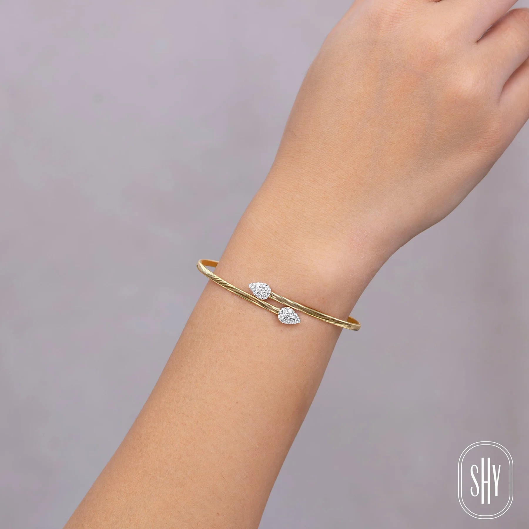 A two-tone gold bypass cuff bracelet containing round-faceted diamonds weighing 0.44 carat total weight in pear-shaped finials